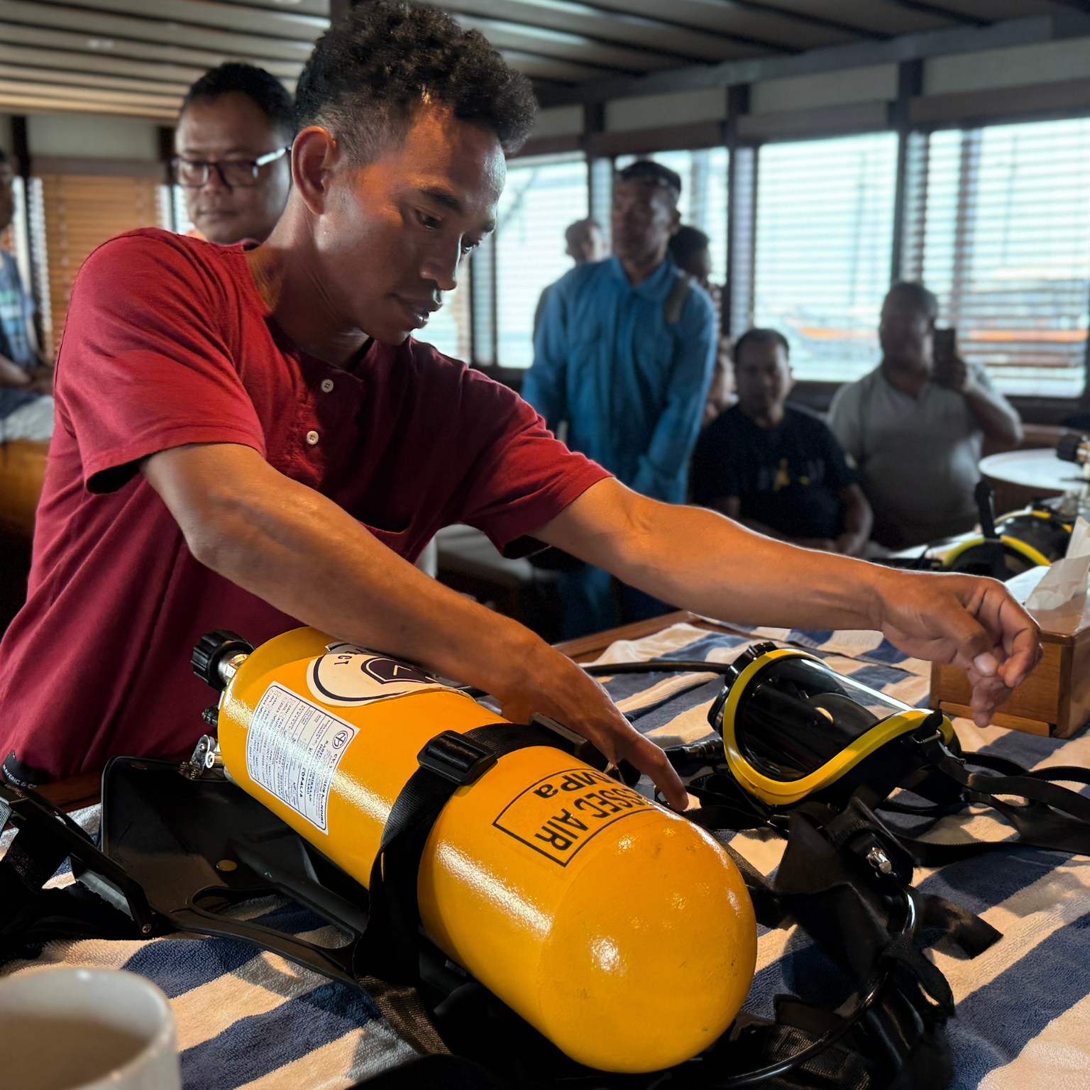 Fire safety training aboard Coralia Liveaboard, crew practicing emergency breathing apparatus use during onboard safety certification
