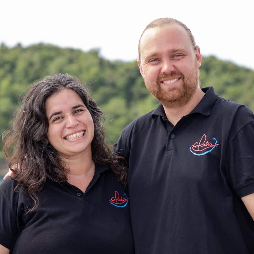 Cruise Directors Jacob and Amanda in the Banda Islands with Coralia Liveaboard with the sails up in the background